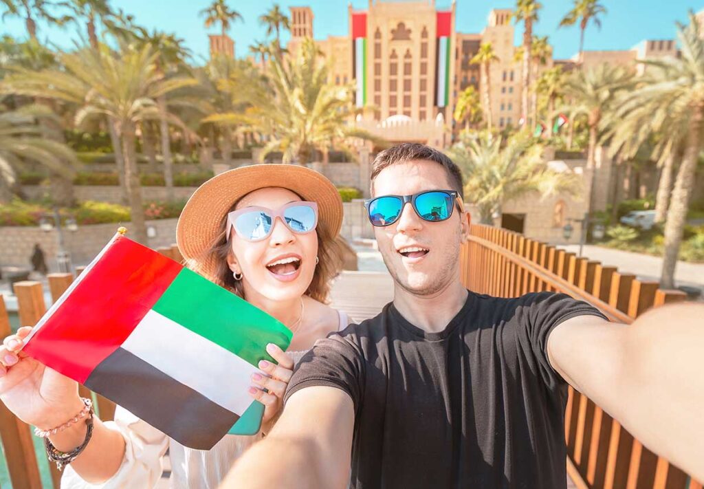 Selfie of a loving couple of man and woman holding UAE national flag. Travel and immigration in Dubai and United Arab Emirates concept
