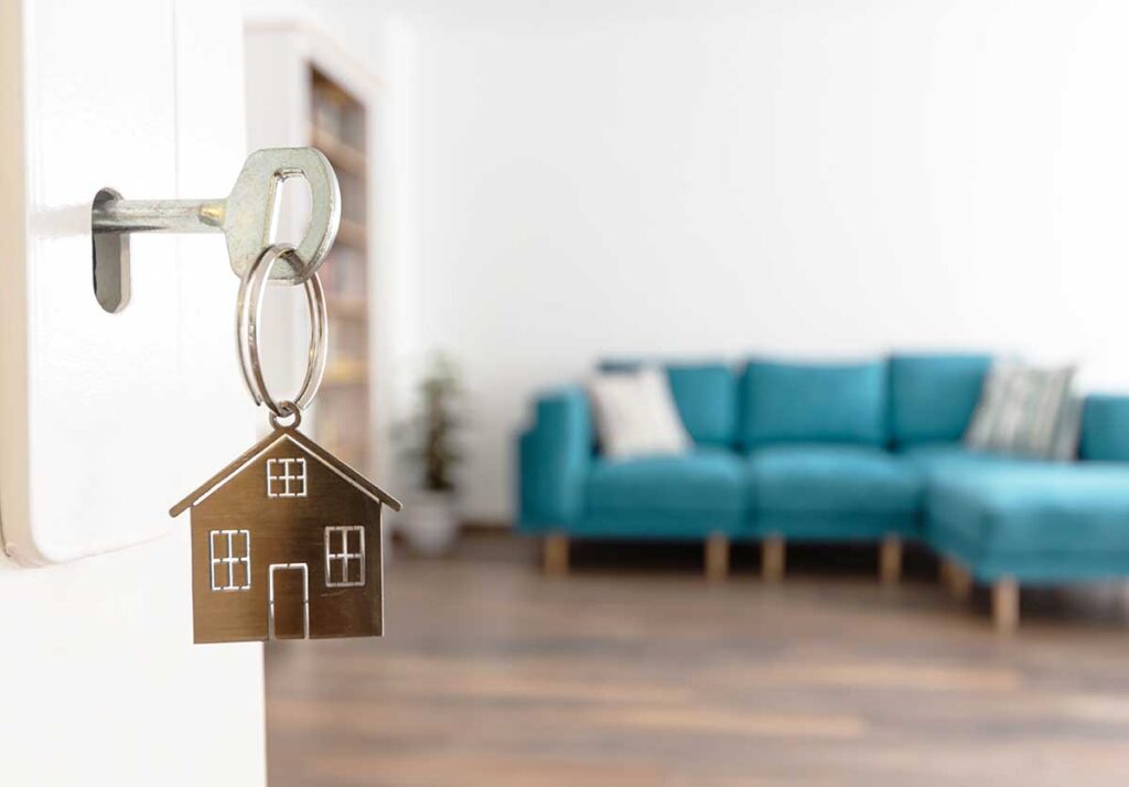 Open door to a new home. Door handle with key and home shaped ke